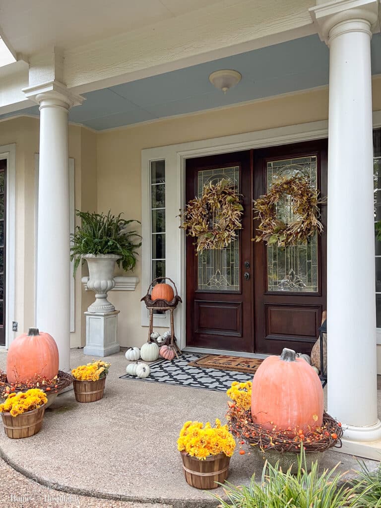 Fall front porch with yellow mums in baskets and pumpkins