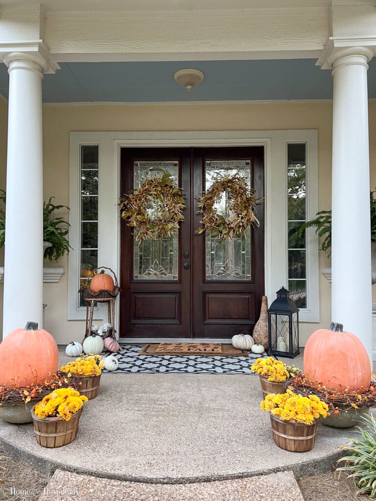 Porch decorated for fall with pumpkins and mums
