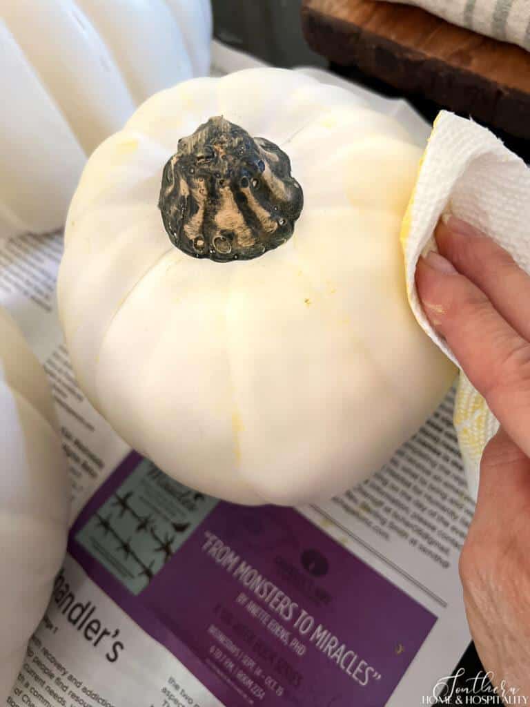 Applying yellow wax to white pumpkin
