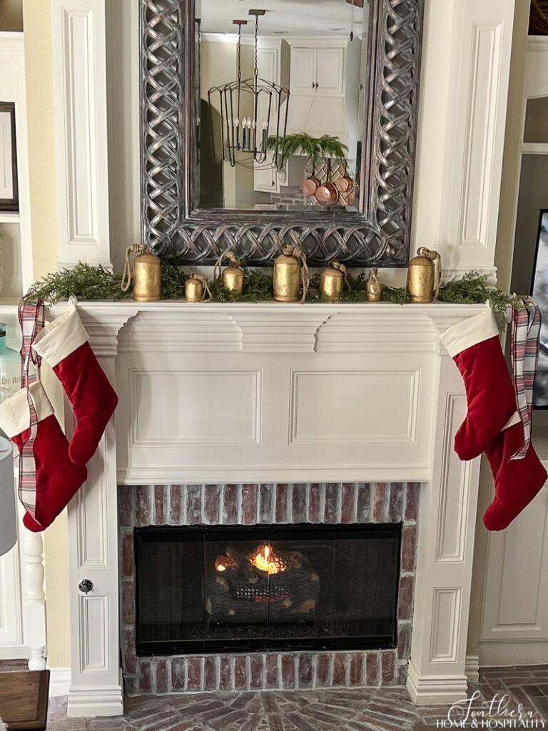 Fireplace with vintage bells and red velvet stockings with plaid ribbon on mantel
