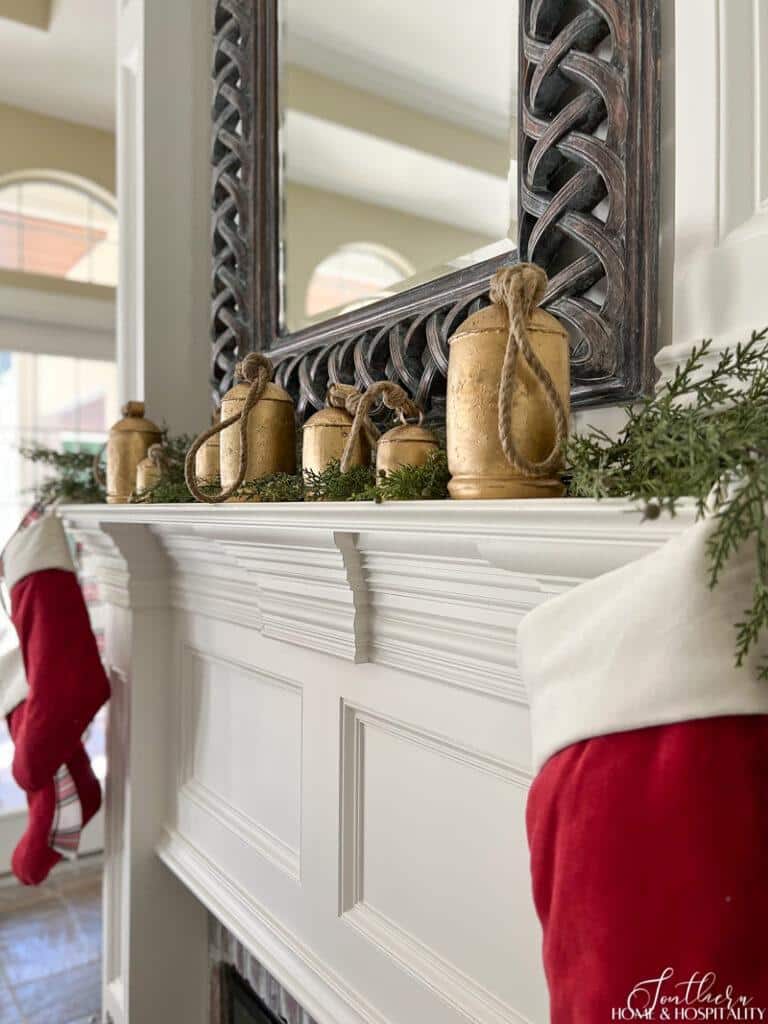 Fireplace with rustic Christmas bells and red velvet stockings on mantel
