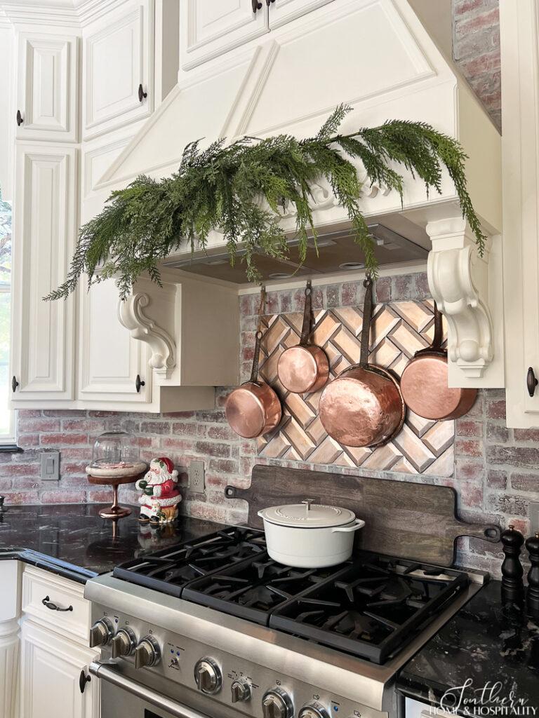 Greenery hung over cooktop with copper pots