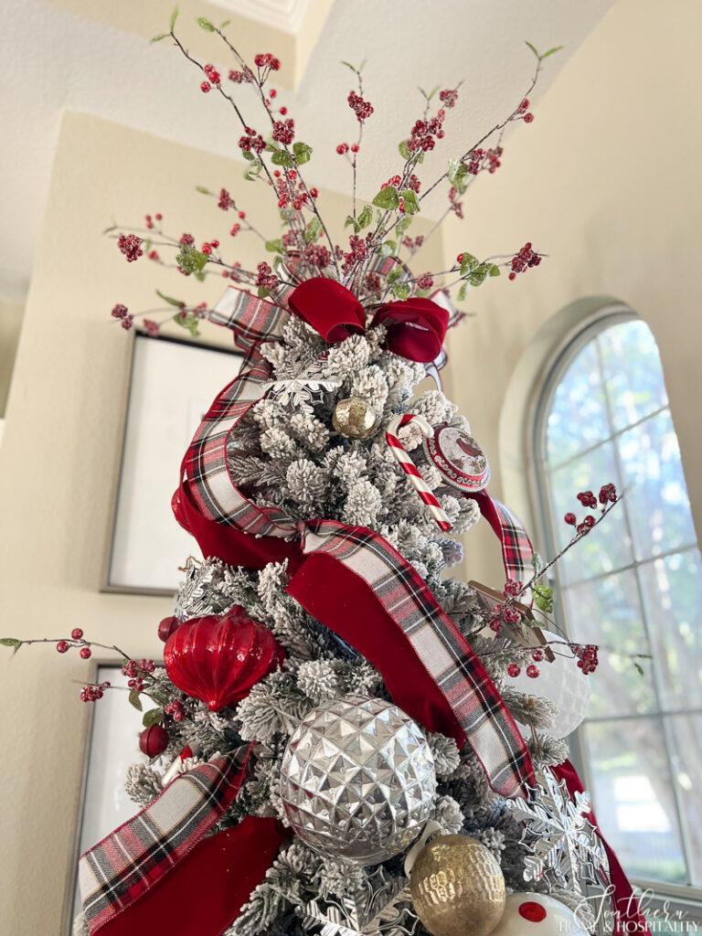 Flocked Christmas tree with berry stem topper and plaid ribbon