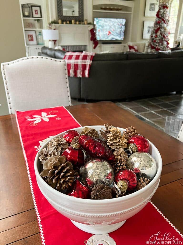 White bowl of mercury glass ornaments and pine cones