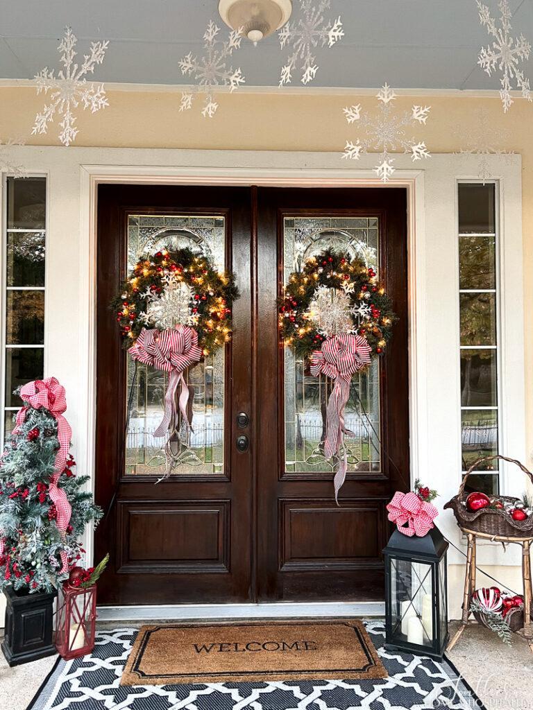 Lighted wreaths on double front doors, snowflakes hanging over front door