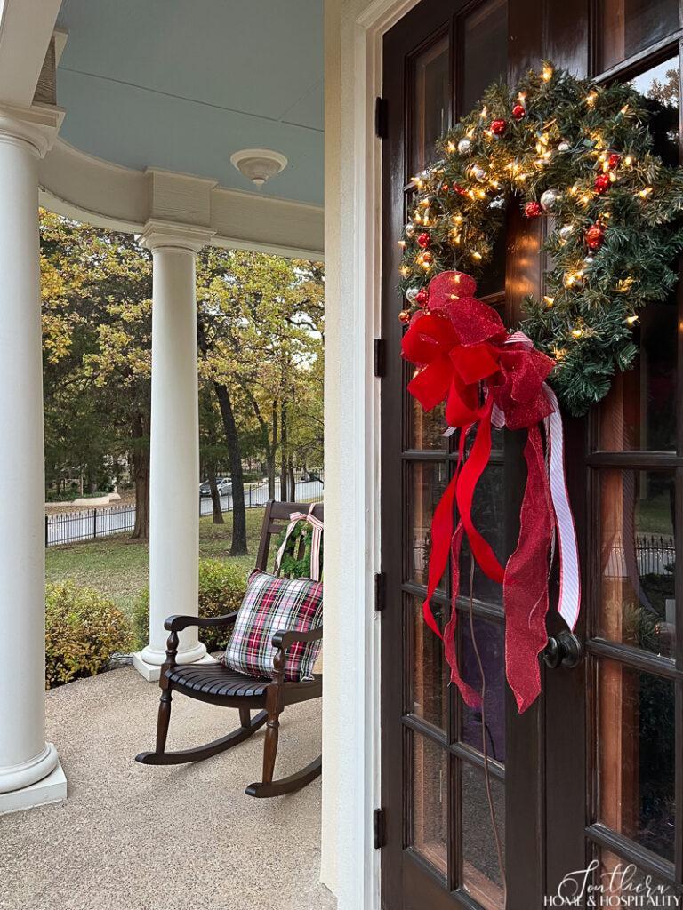 Lighted wreath with red bow on French front door