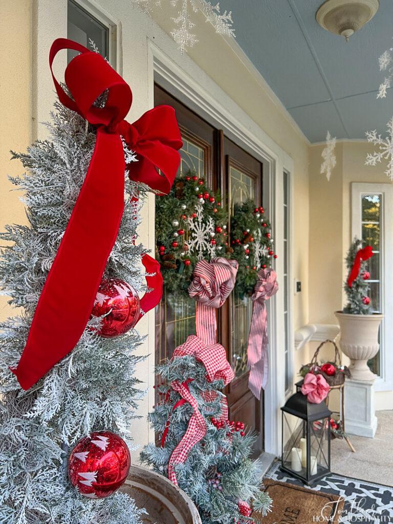 Red bow and ornaments on topiary on front porch