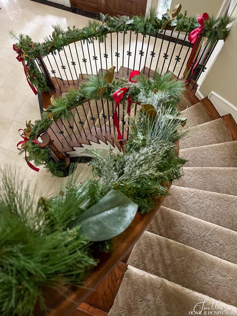 Pine, cedar, and magnolia garland on curved staircase banister