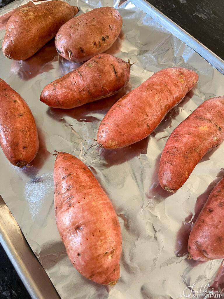 Sweet potatoes pricked with a fork on a baking sheet