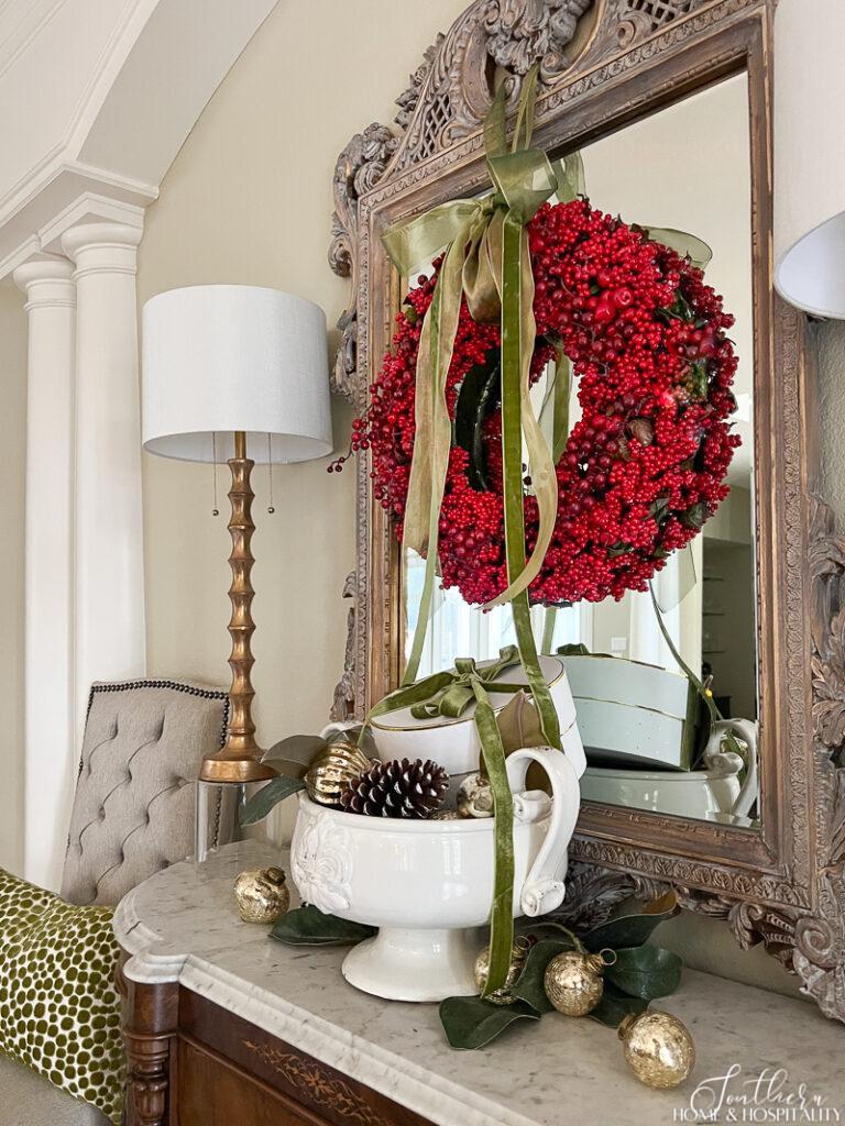 Red berry wreath with green ribbon on sideboard mirror