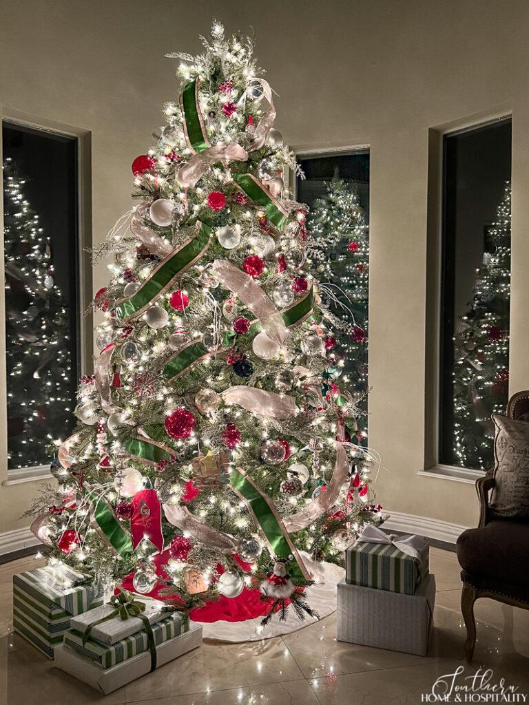 Decorated Christmas tree with white lights, green ribbon, and red ornaments