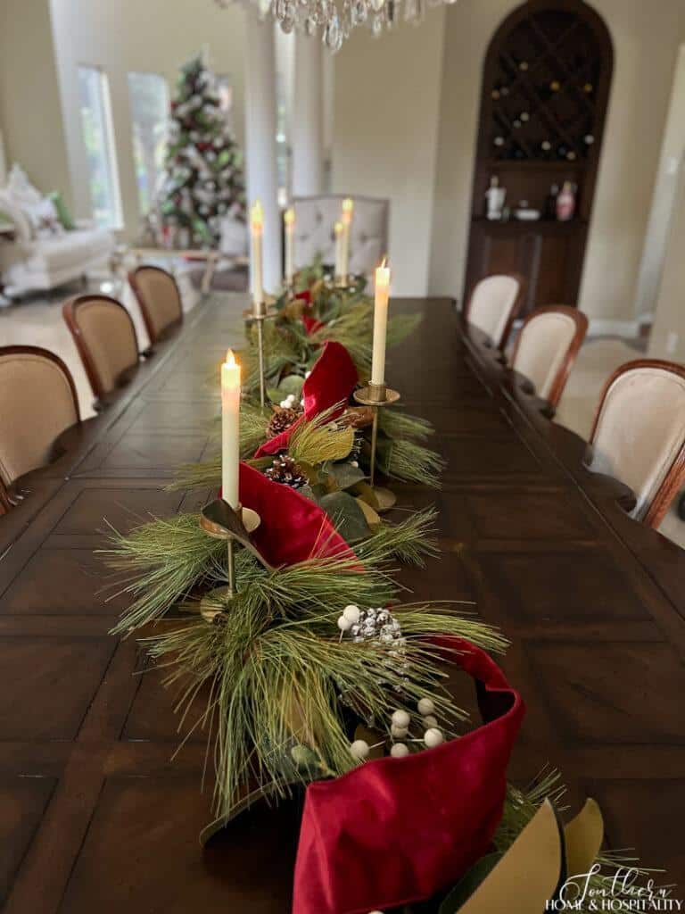 Pine Christmas garland and brass candlesticks with flameless candles on dining table