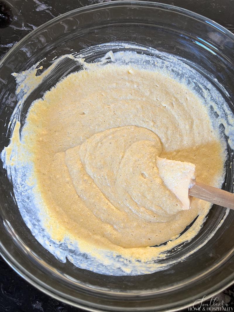 Mixing ingredients for cornbread in a glass bowl