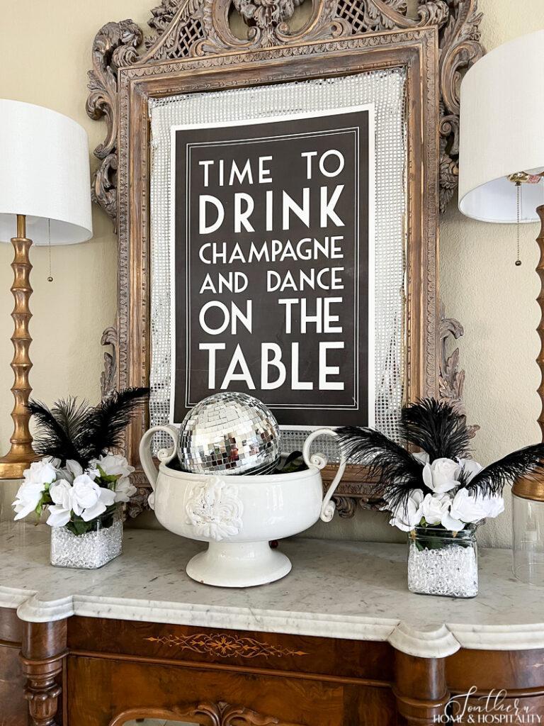 Time to drink champagne and dance on the table sign, disco ball decor, white roses and black ostrich feathers in vases