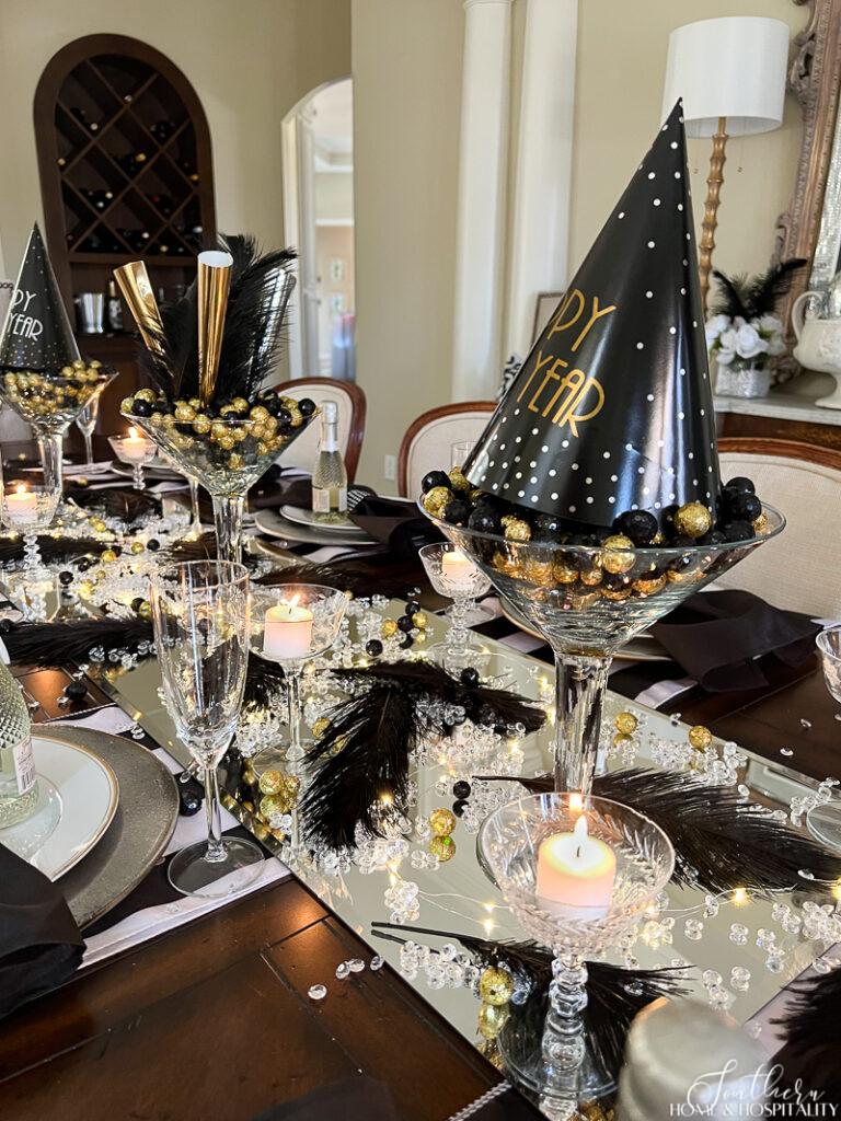 Large martini glass centerpiece with black and gold and New Year's Eve party hats