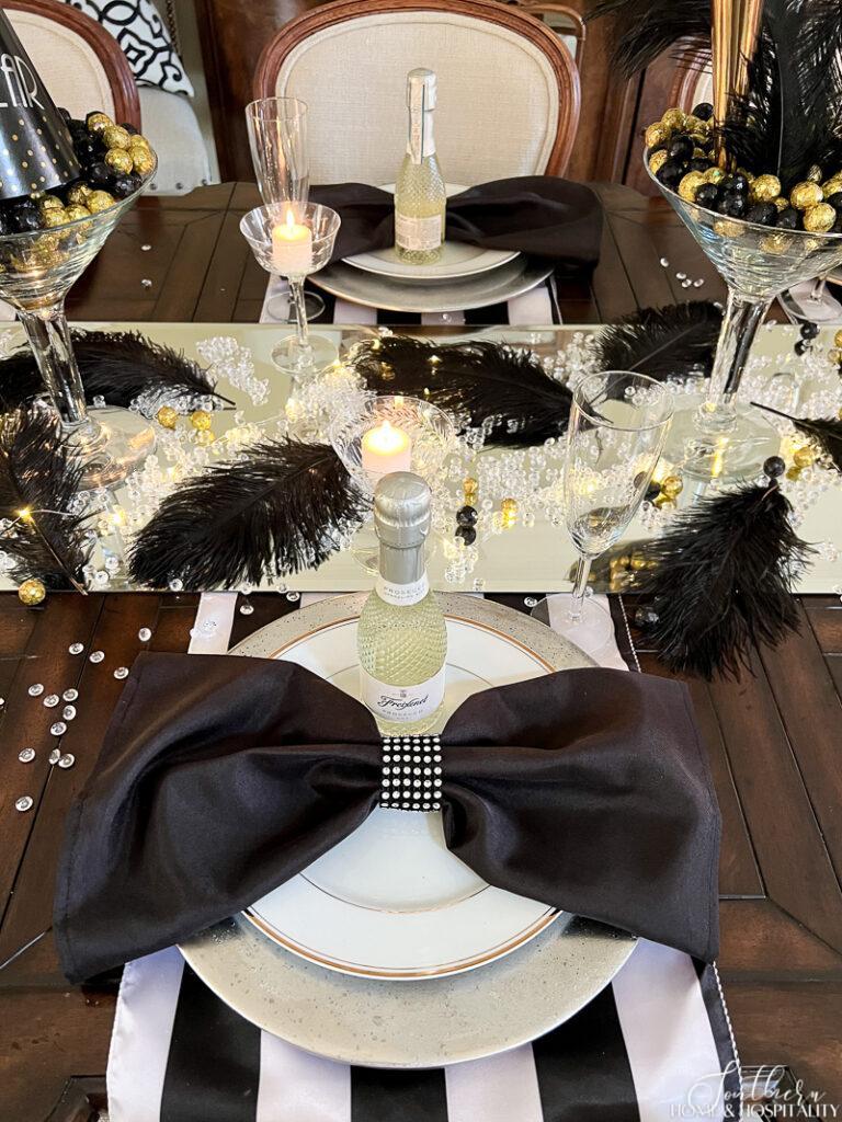 Bow tie napkin with small champagne bottle on New Year's Eve table setting