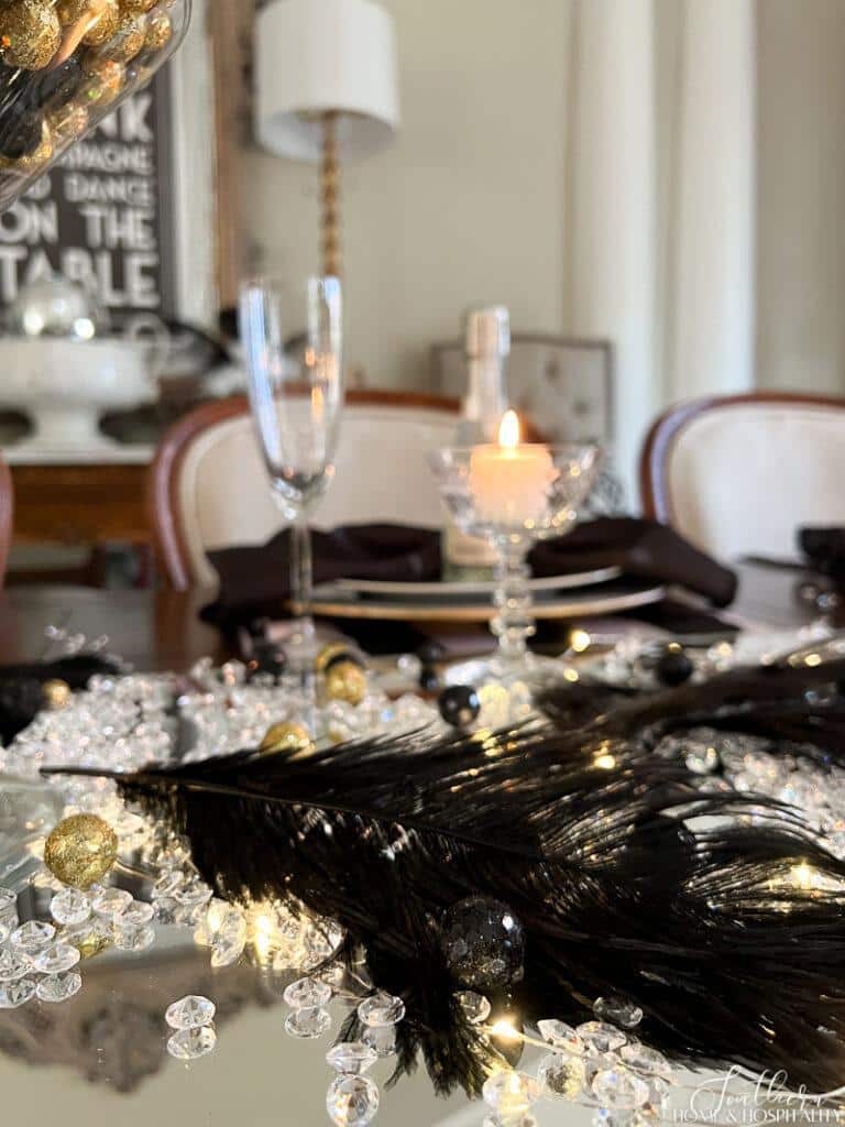 Diamond scatter, fairy lights, and black feathers on mirror centerpiece