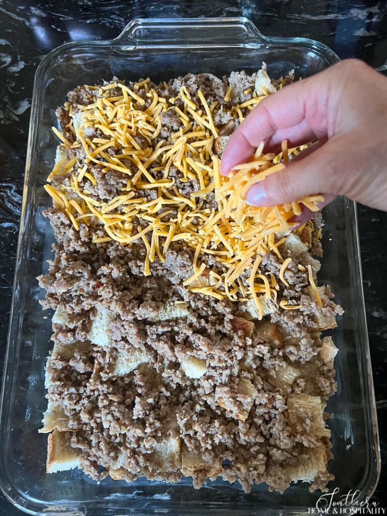 Sprinkling cheese over bread and sausage