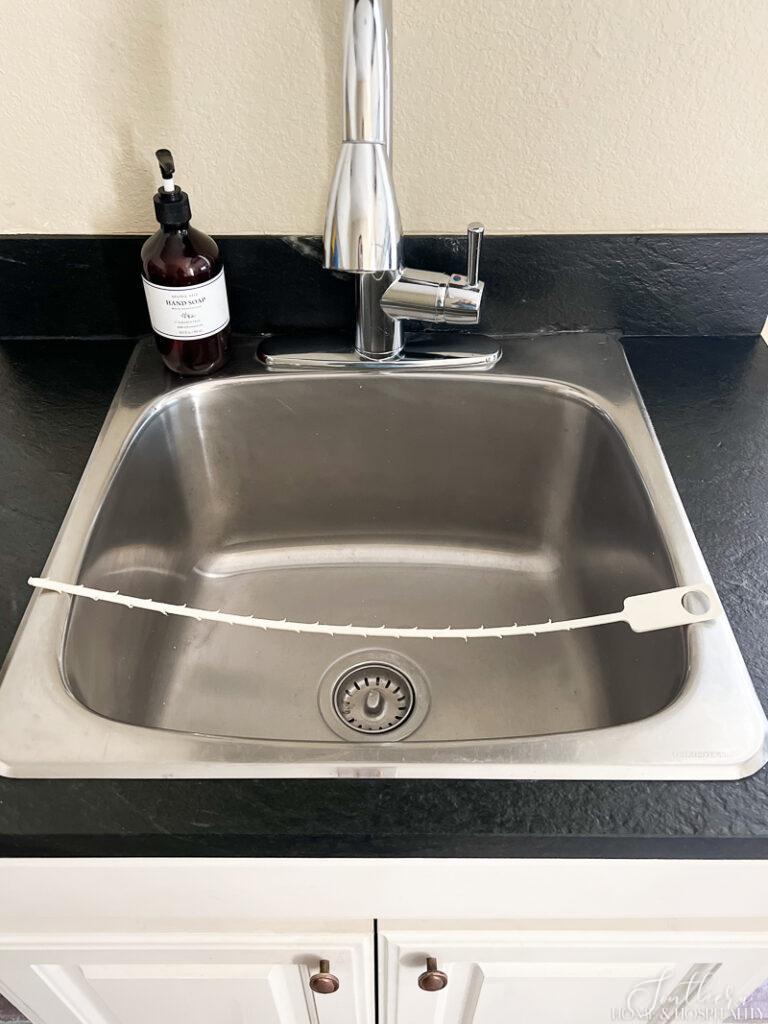 Drain clog plastic tool on laundry room sink