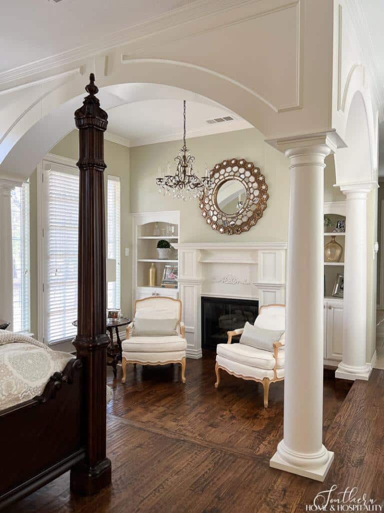 Arches, columns, and molding in primary bedroom with sitting area and fireplace