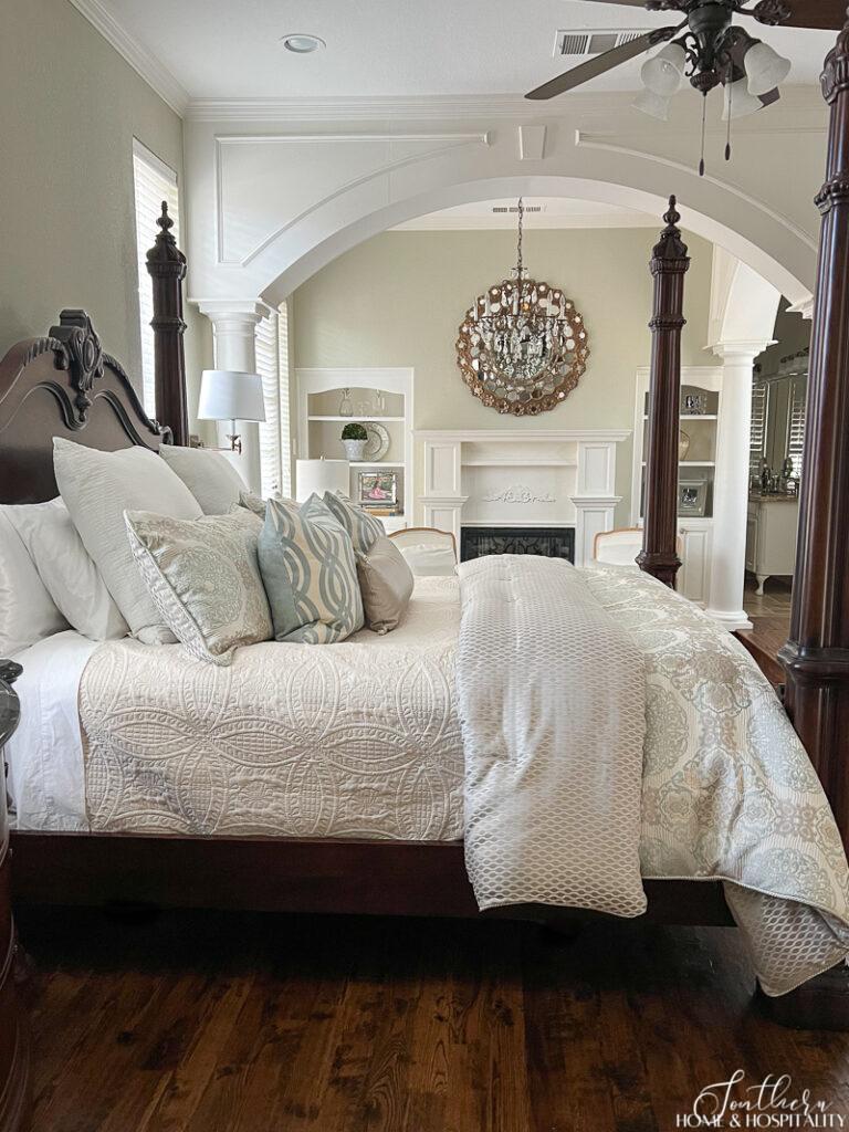 Bed made with coverlet, comforter, and throw pillows in master bedroom