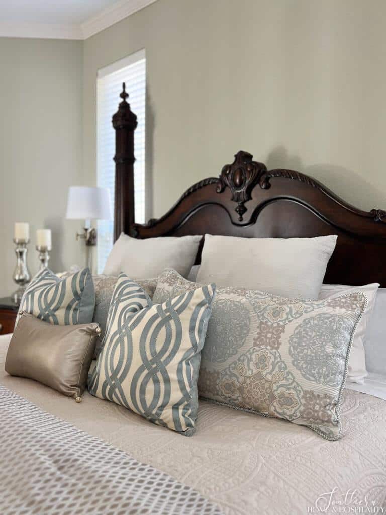 Soft blue and white throw pillows and ivory quilt on bed