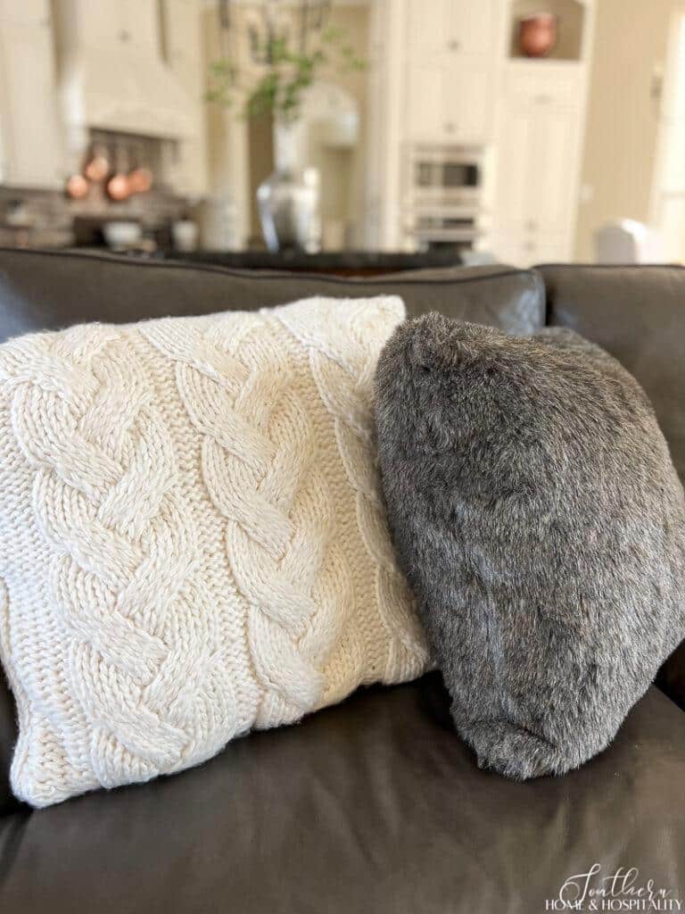 Cable knit and fur throw pillows on a leather sofa