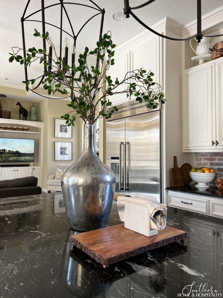 Faux green branches in a vase on kitchen island