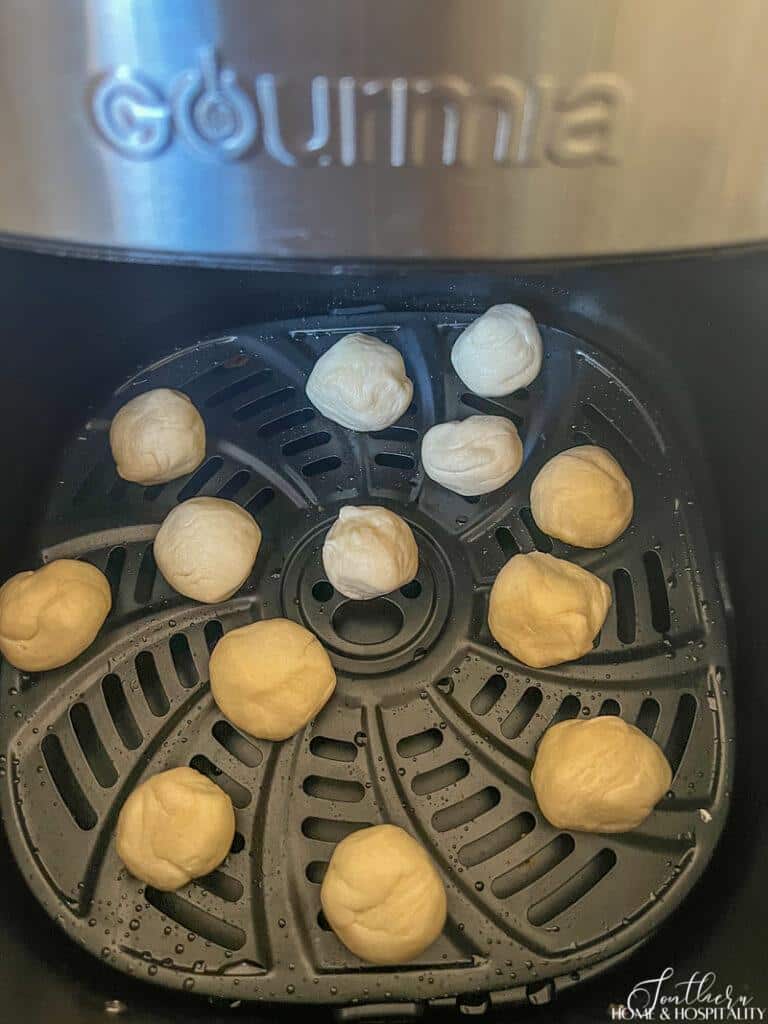 Uncooked biscuit pieces in air fryer basket