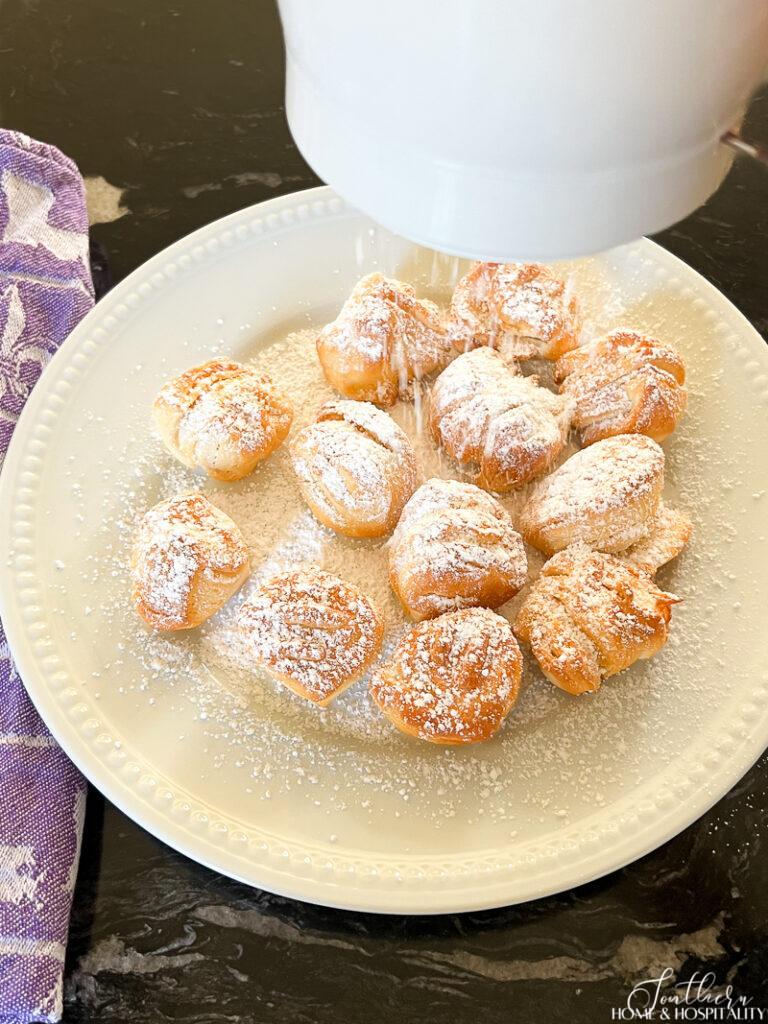 Sifting powdered sugar over fried beignets