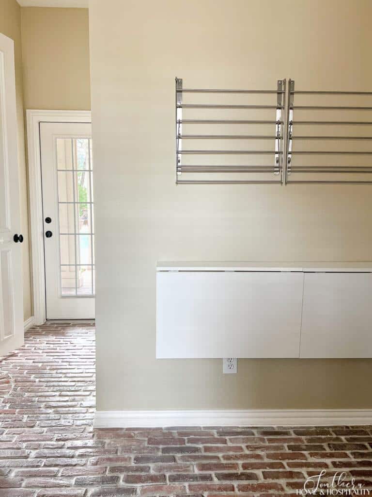 IKEA laundry racks and fold out table in laundry room with brick floors