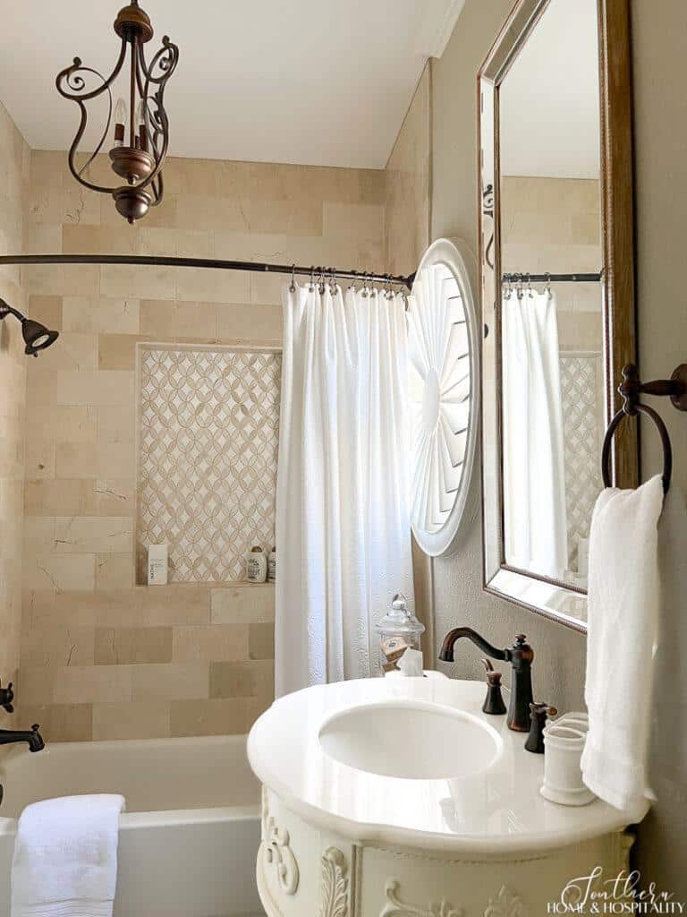 Bathroom with white marble top pedestal sink and tan marble shower