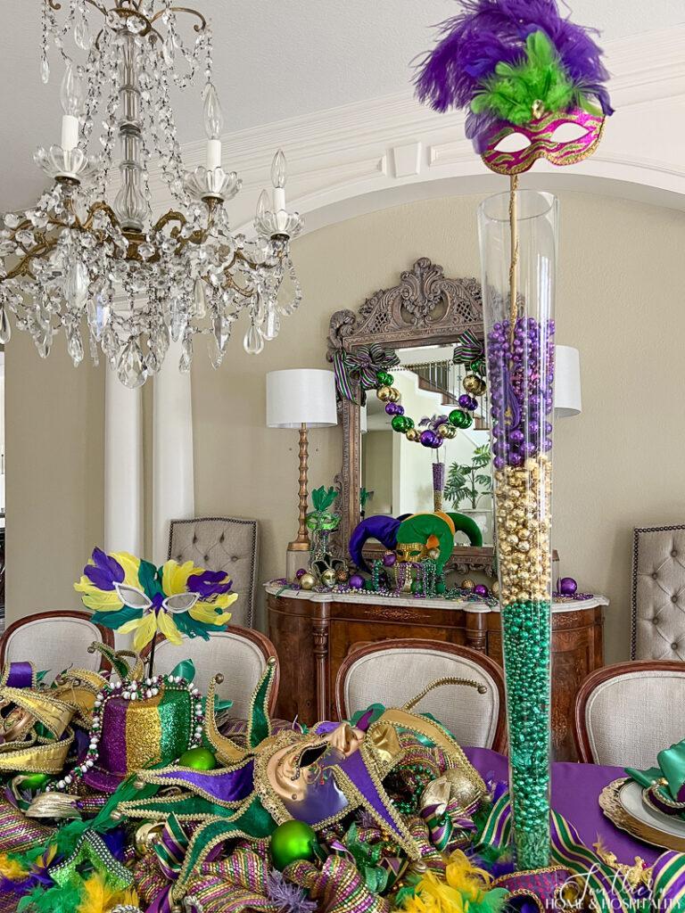 Tall glass vase filled with purple, green, and gold beads on Mardi Gras dinner table