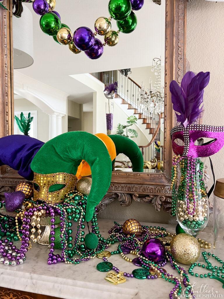 Mardi Gras dining room sideboard buffet decor with, beads, masks, ornaments, jester hat, and hurricane glass