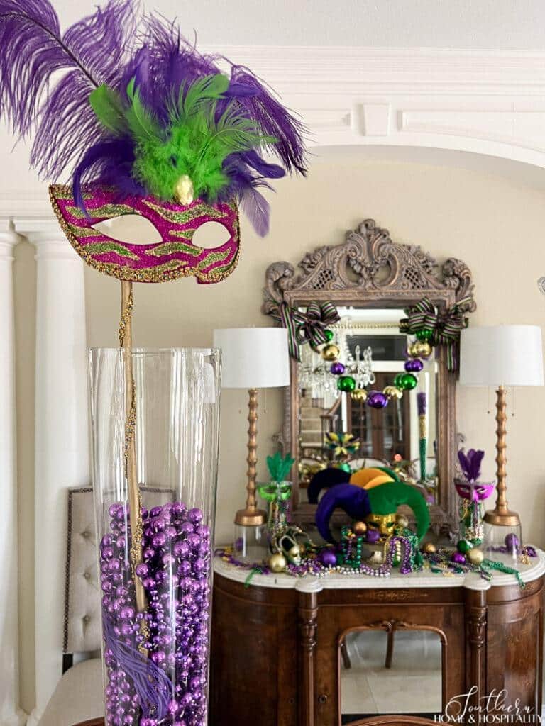 Mardi Gras beads and a mask in a glass vase, dining room sideboard decorated for Mardi Gras