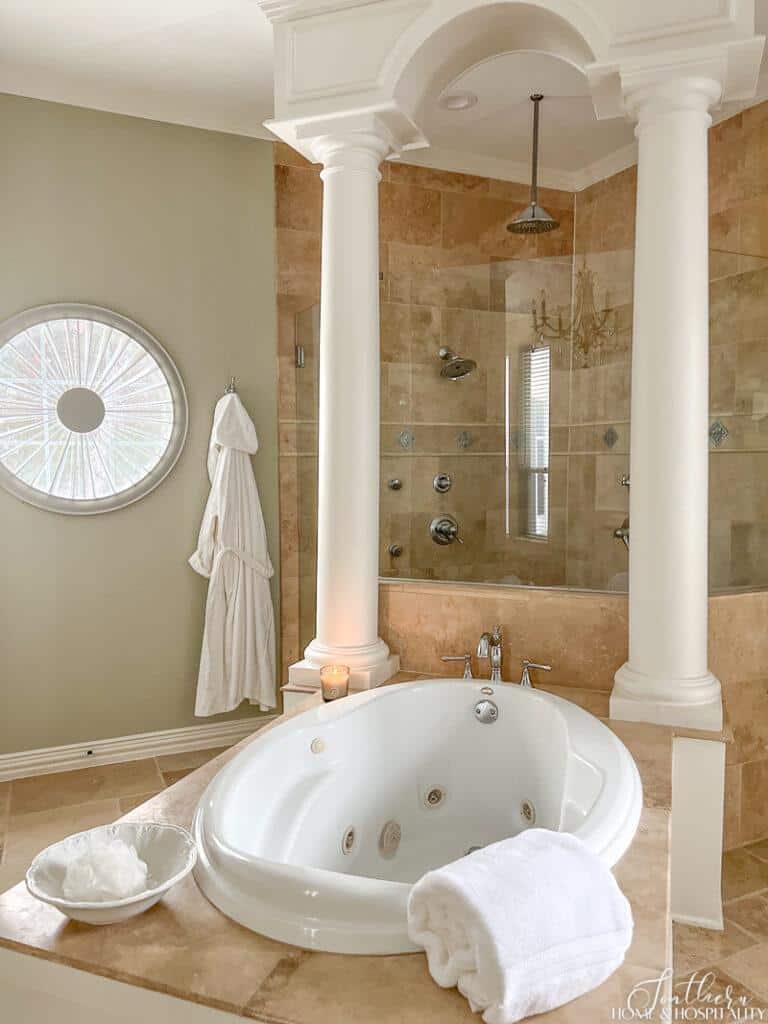 Jetted bathtub, wood arch and column millwork and travertine shower in master bathroom