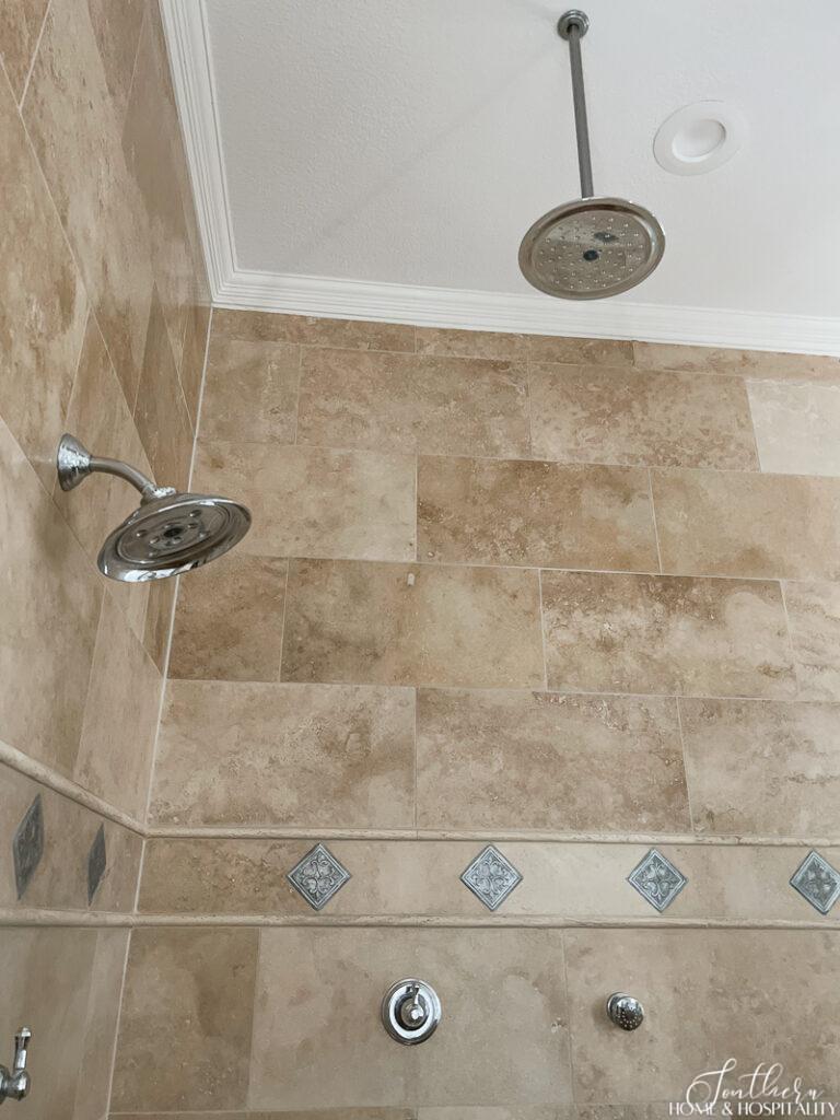 Travertine shower with rainhead and metallic tile accents