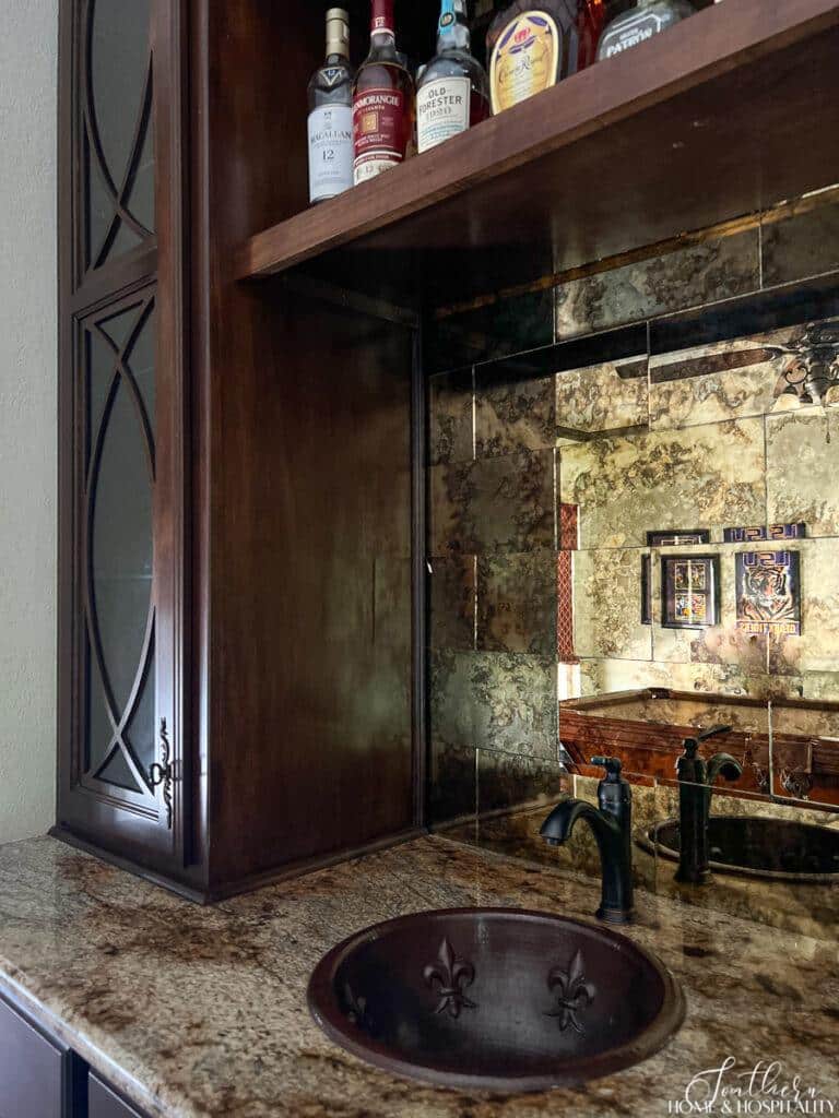 Home bar with copper fleur de lis sink and gold antique mirror backsplash