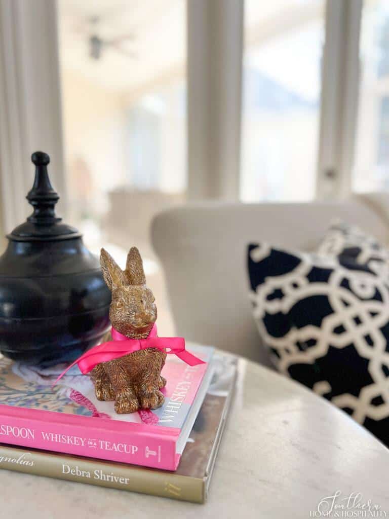 Gold rabbit figurine with pink bow on a stack of books for spring end table decor