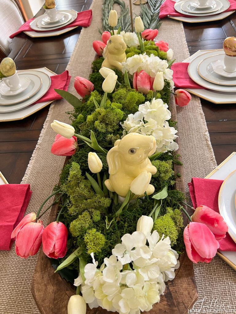 Spring centerpiece with rabbits, moss, and pink and white flowers