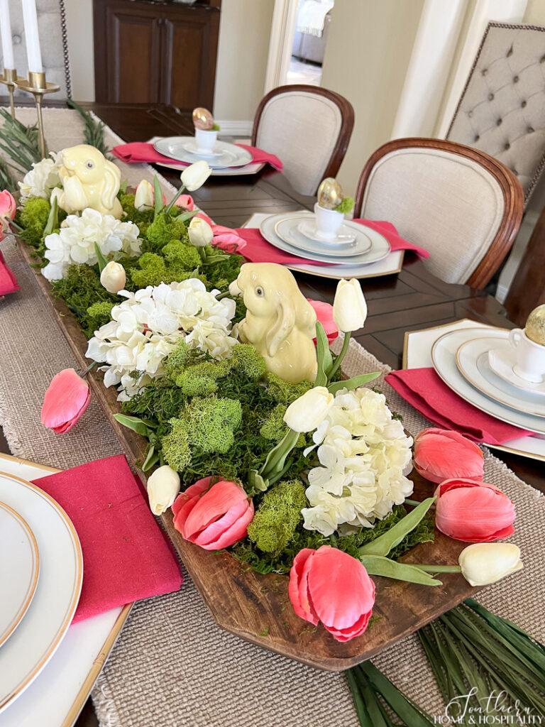 Easter dough bowl centerpiece with pink and white tulips, hydrangeas, green moss, and bunnies