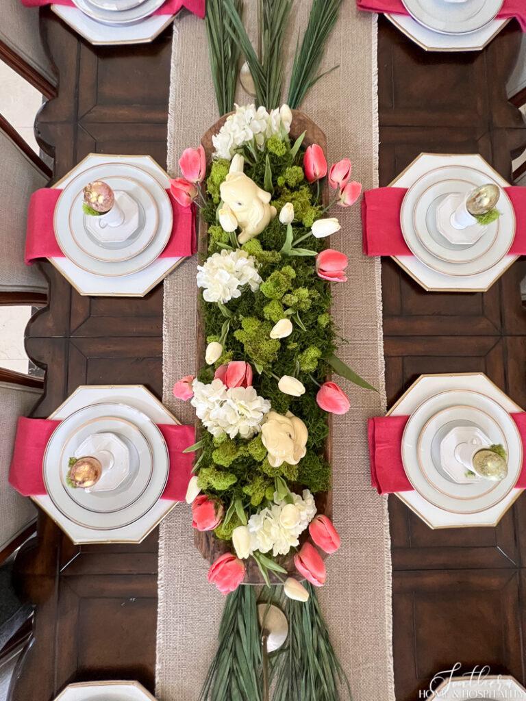 Spring tablescape with pink and green tulips, hydrangeas, moss, and palm leaves