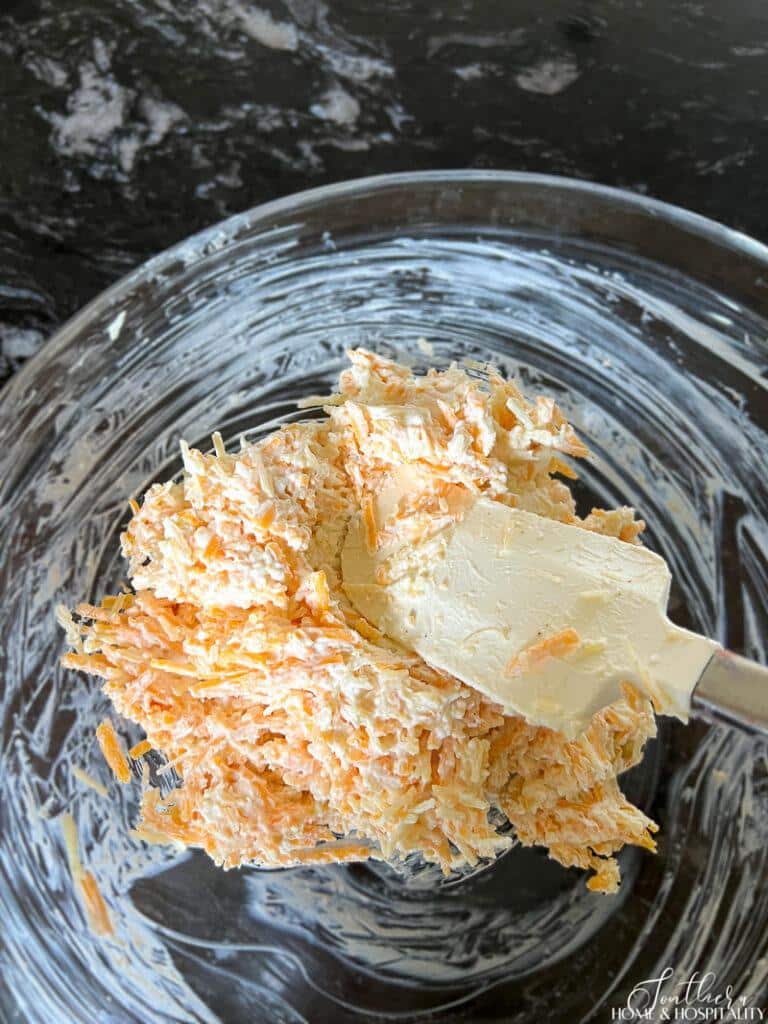 Stirring cream cheese mixture with grated cheese