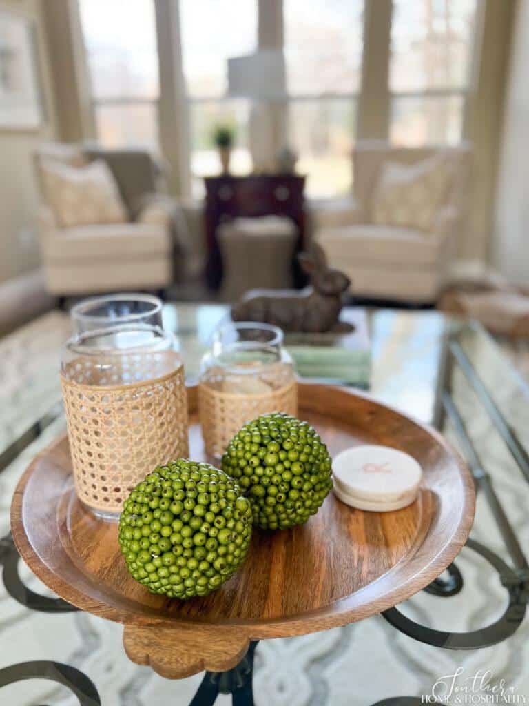 Spring coffee table vignette with green berry balls and caned candleholders