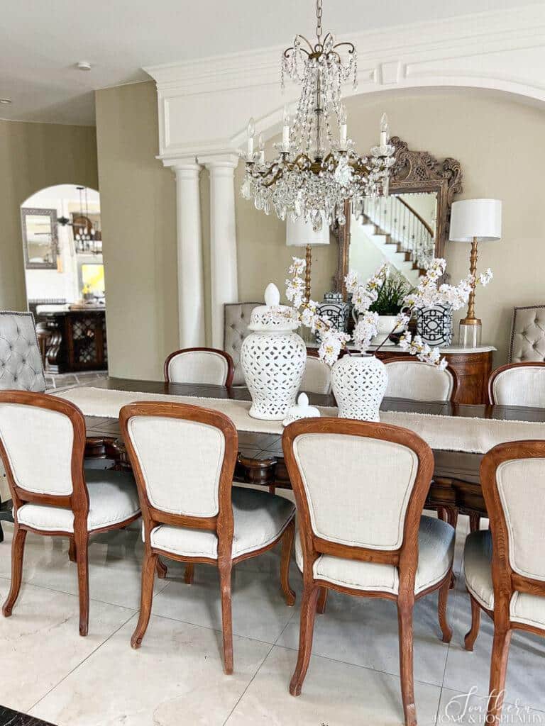 Dining room with spring cherry blossoms, white ginger jars, and vintage chandelier