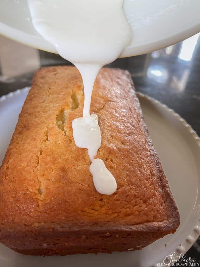 Pouring sweet lemon glaze over lemon loaf