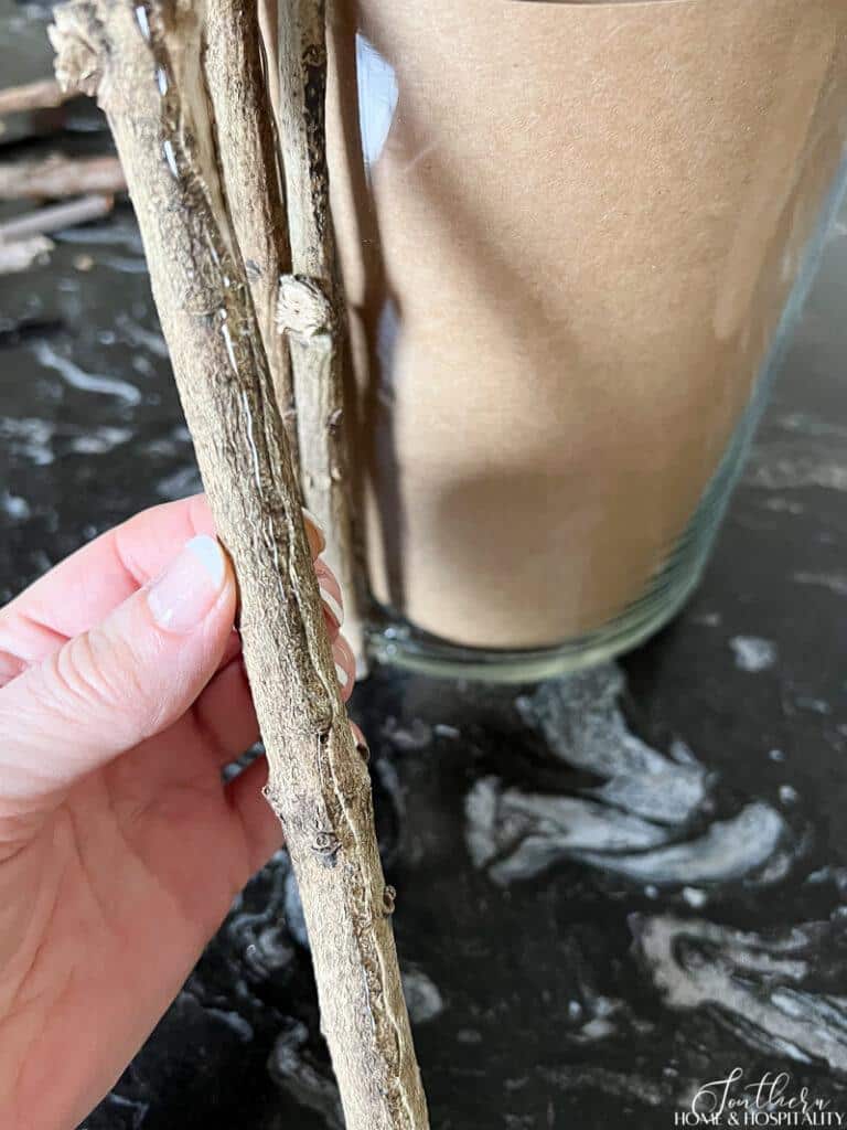 Hot glue on twig to attach to glass vase