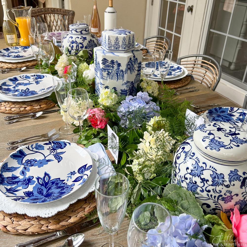 Blue and white table setting with chinoiserie jars and blue and white flower garland centerpiece