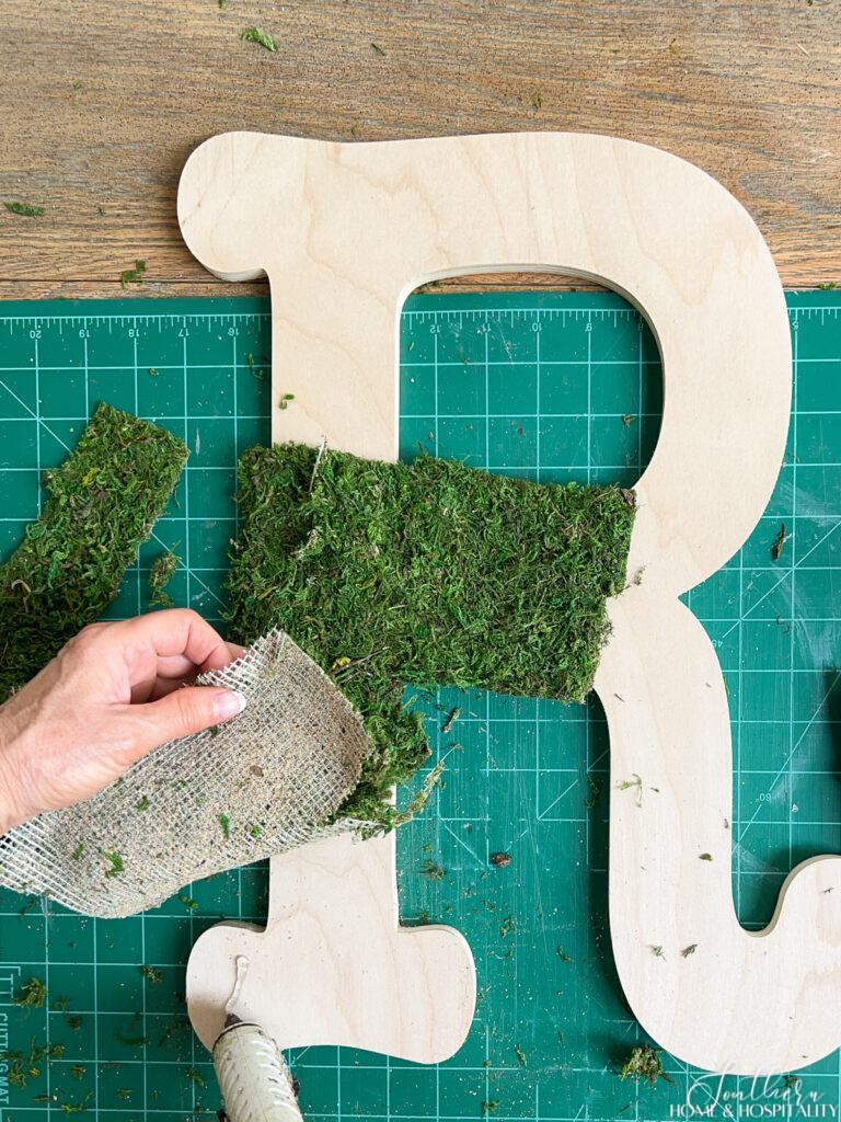 attaching moss with hot glue to wood letter