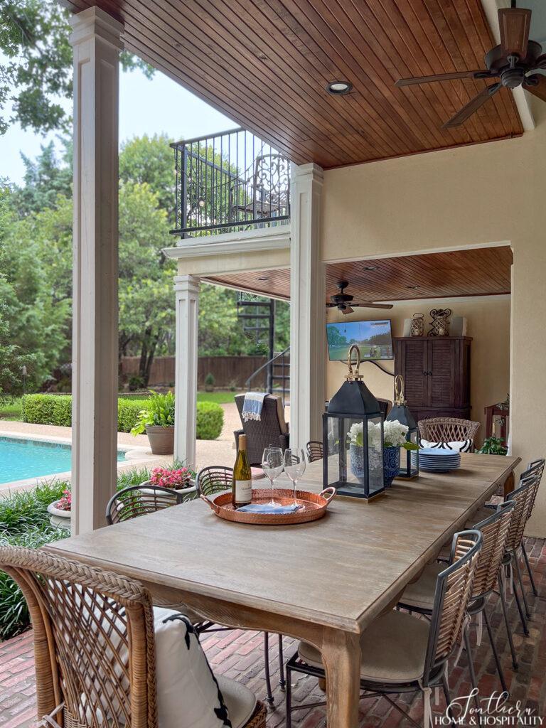 French country narrow dining table on back porch with wicker and rattan chairs